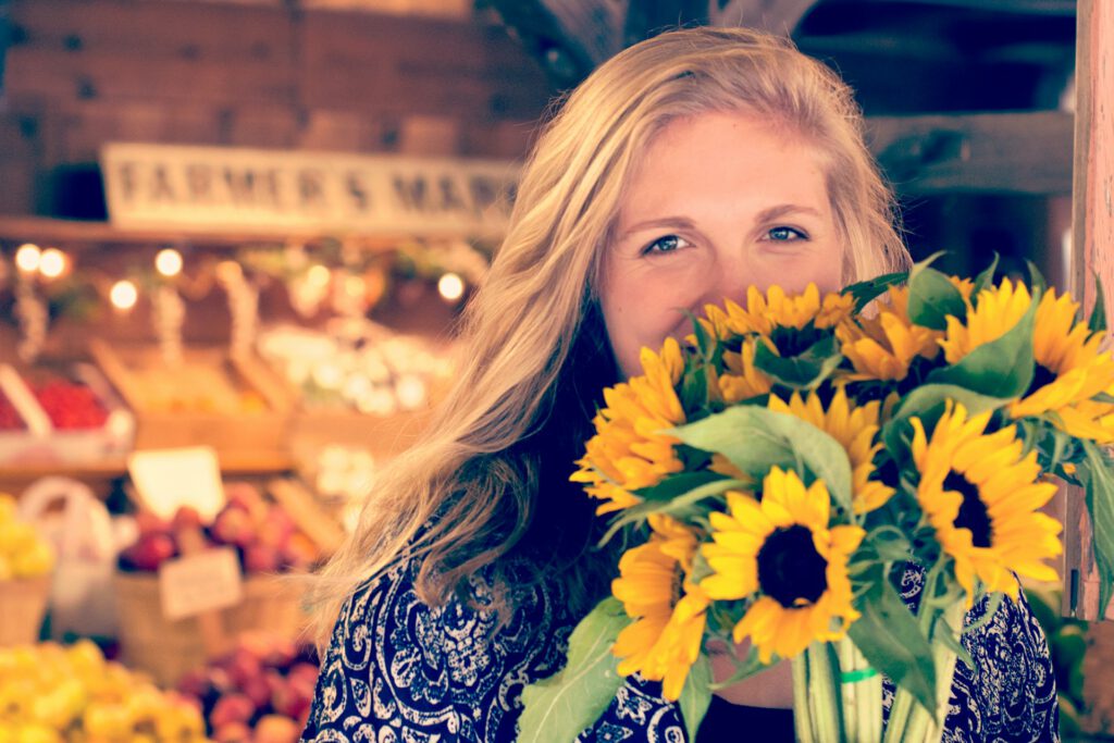 Eine junge Frau kauft einem Wochenmarkt Blumen ein