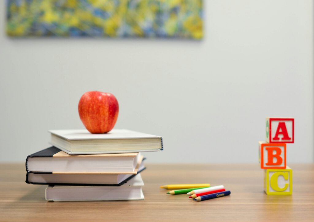 Bücher, Klötze, Stifte und ein Apfel auf einem Schreibtisch in der Grundschule